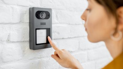 Woman pressing a door buzzer.